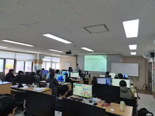 실습실 앞에서 에이전시프로 서정익 상무가 발표하고 학생들이 컴퓨터 앞에서 특강을 듣는 현장 사진
